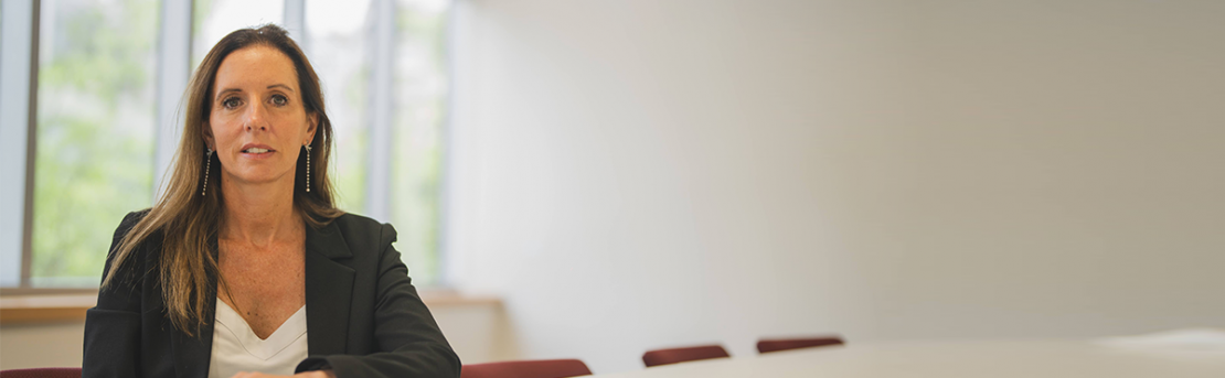 La gerenta de APV de LarrainVial, Claudia Ovalle, sentada ante una mesa blanca y mirando a cámara.