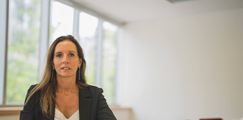 La gerenta de APV de LarrainVial, Claudia Ovalle, sentada ante una mesa blanca y mirando a cámara.